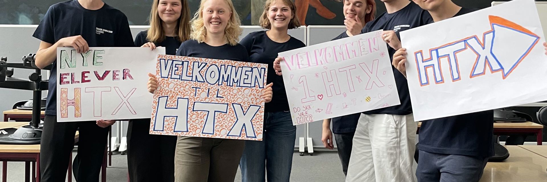 Tutorerne holder "Velkommen til HTX" skilte i et klasselokale