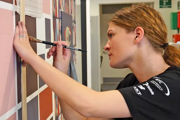 Kvindelig bygningsmaler maler vægdekoration med bogstaver