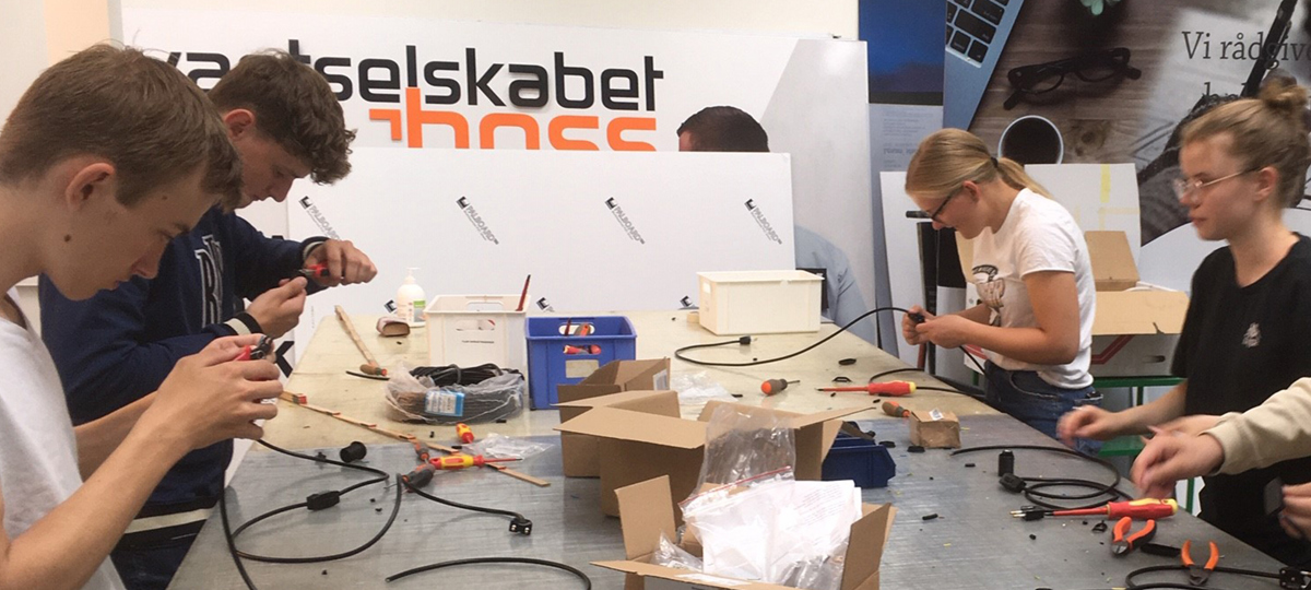 Gruppe af elektrikere sidder ved et bord og sammensætter ledninger