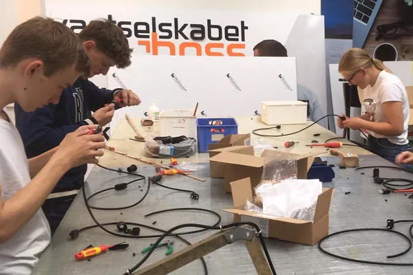 Gruppe af elektrikere sidder ved et bord og sammensætter ledninger