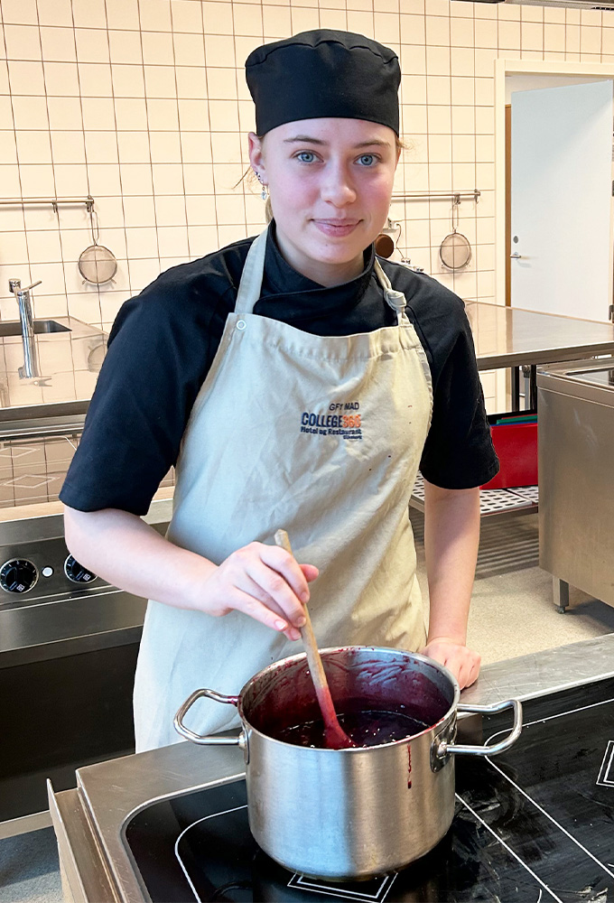 Sandra står ved en stor gryde og rører rundt