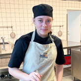 Sandra står ved en stor gryde og rører rundt