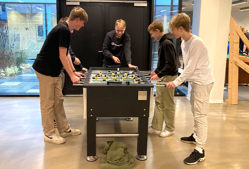 4 drenge spiller bordfodbold i fællesrummet på College360 Bredhøjvej 8