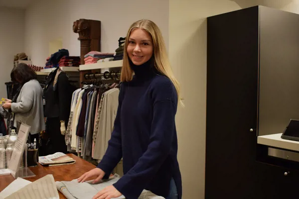 Pige i lære i tøjbutik står ved kassen