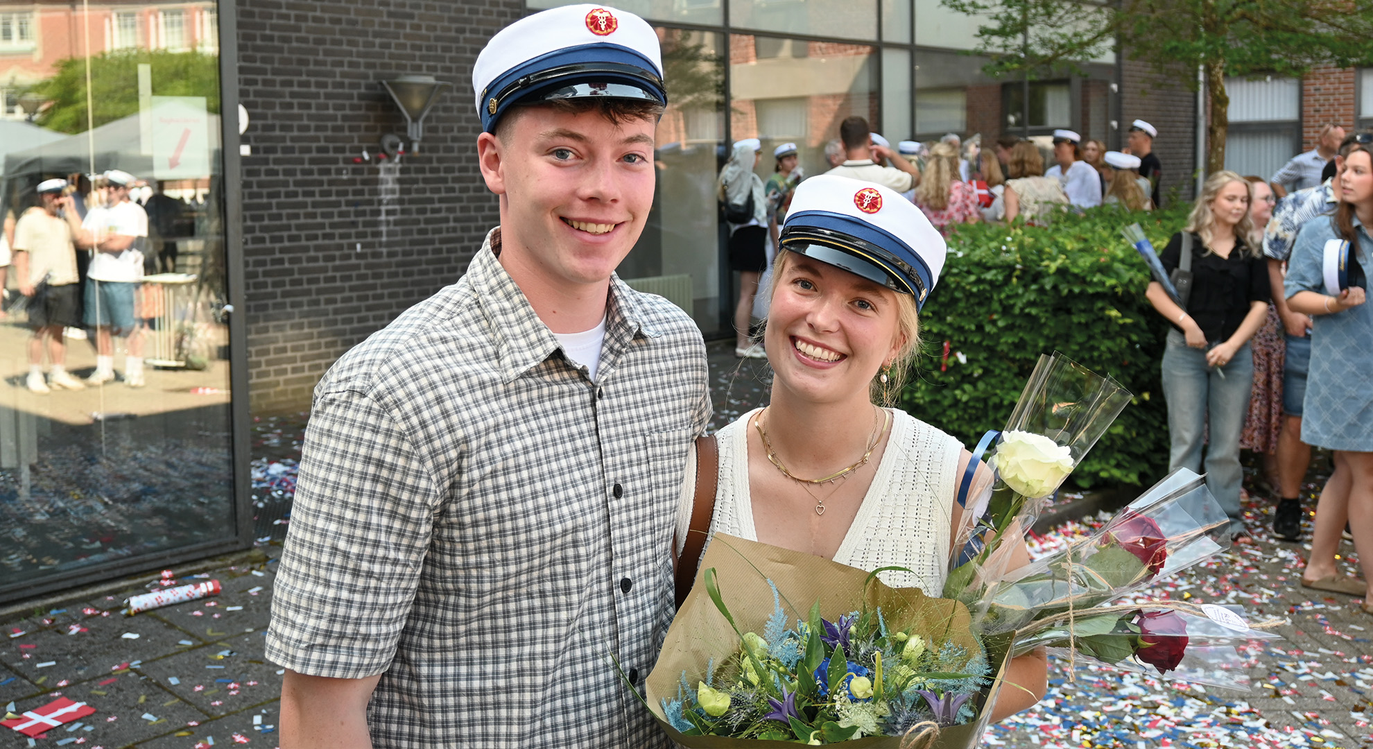 To smilende HHX studenter med hue på